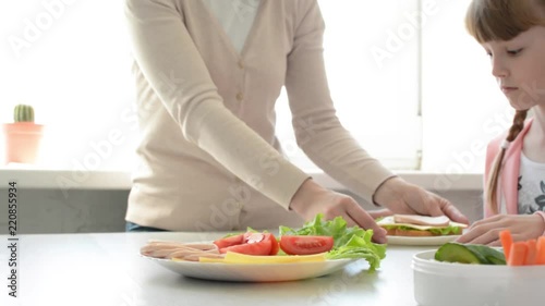 Mother making sandwiches for daughters eating