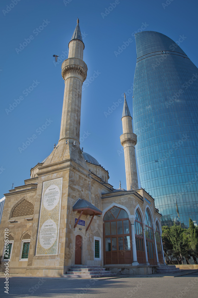 BAKU, AZERBAIJAN : The Mosque of the Martyrs Sehidler Mescidi Mosque, Turkish Mosque with the Flame Towers skyscraper in the background in Baku, Azerbaijan, at sunset.