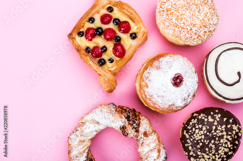 A wide range of pastry cakes, donuts, pretzels, pink, sweets, top view, advertising space