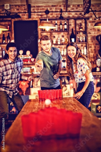 Group of happy friends playing beer pong game 