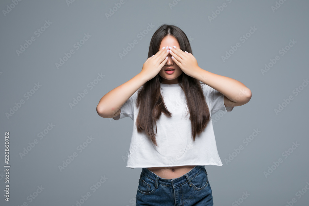 Portrait of lovely asian woman with long hair smiling and covering face with palms isolated over gray background Portrait of lovely asian woman with long hair smiling and covering face with palms isolated over gray background