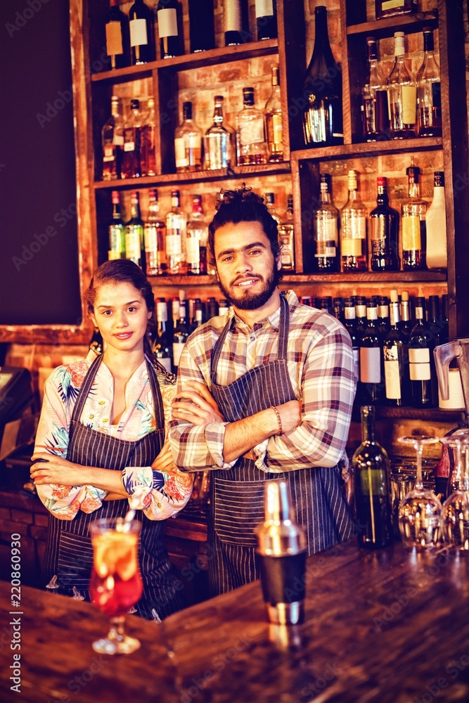 Portrait of waiter and waitress standing with arms crossed at Portrait of waiter and waitress standing with arms crossed at