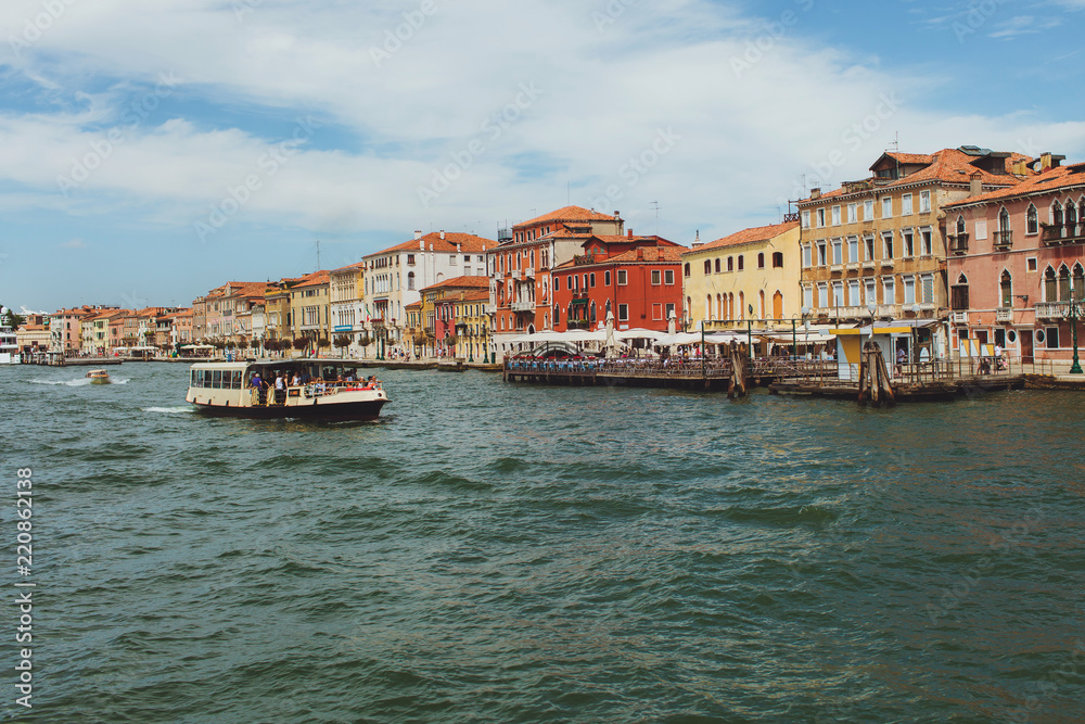 Venetian channel view at the city of urban architecture, boats, buildings, pier, transport of Venice, free space
