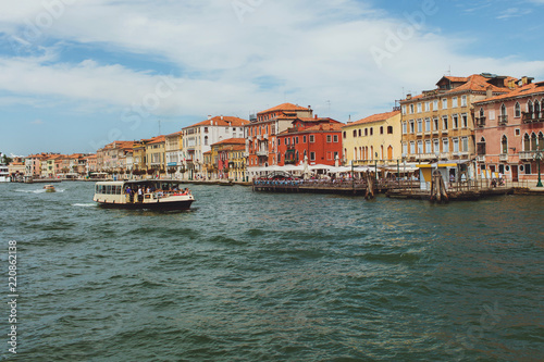 Venetian channel view at the city of urban architecture, boats, buildings, pier, transport of Venice, free space
