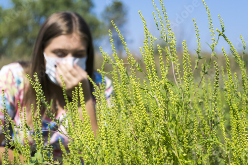 Young woman sneezes because of an allergy to ragweed. photo