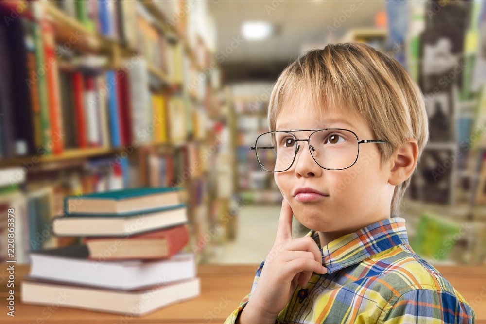 Cute little schoolgirl in glasses with books on background Cute little schoolgirl in glasses with books on background