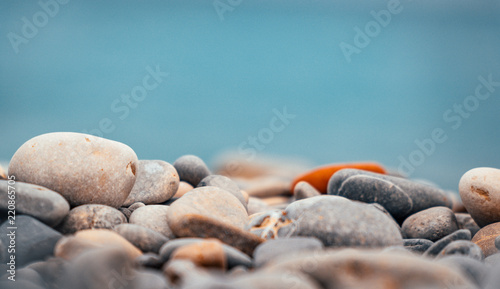 Close up of pebble and stone rock beach with blue ocean