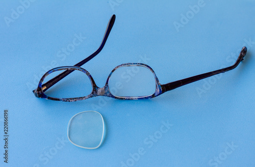 Broken eyeglasses, burned plastic frame, damaged beyond repair, on blue background