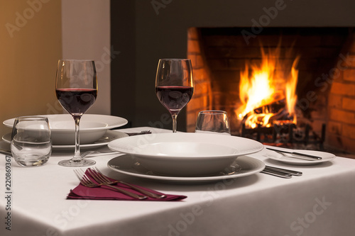 Dinner table for romantic evening, with fireplace in behind.