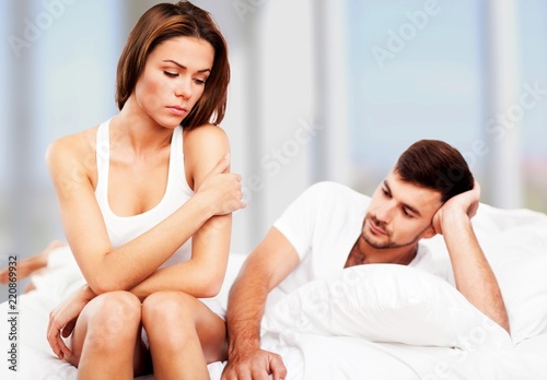 Dissatisfied beautiful young woman in bed with sad expression on