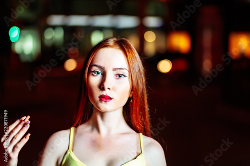 Red haired girl raise her hand with fancy nail art in front of dark night city background
