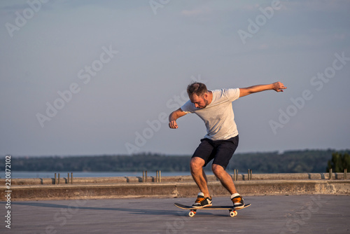 Young skateboarder performing a flip trick in a jump on the road, the free space.