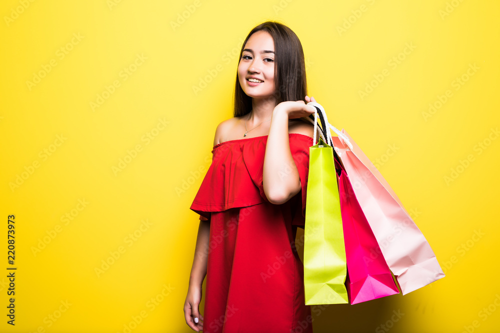 Beautiful young asian woman with shopping bags on yellow background. Shopaholic shopping Fashion.