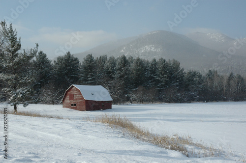 Elizabethtown Barn in the Winter Mist. A picturesque old barn in Elizabethtown in the Adirondacks of upstate New York. Winter scene in the snow with mountains and mist visible in the background. photo