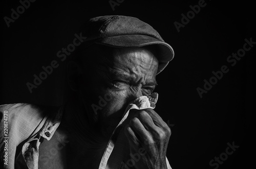 Elderly man suffering from a runny nose.