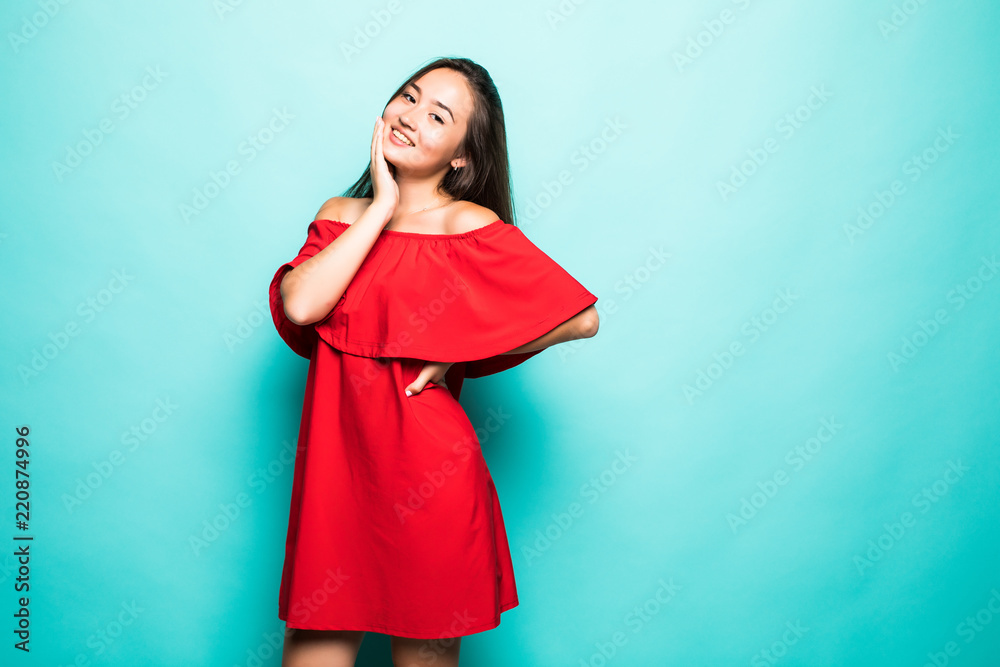 Gorgeous woman. Portrait of beautiful smiling young asian woman standing in cute red dress isolated on blue background Gorgeous woman. Portrait of beautiful smiling young asian woman standing in cute red dress isolated on blue background