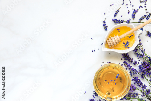 cup of lavender tea with honey and fresh flowers over white marble table. herbal drink. top view