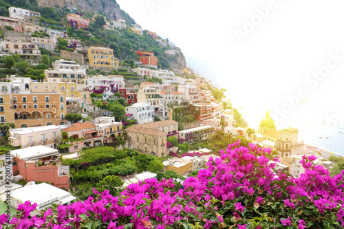 Stunning panoramic view of Positano village with flowers and sunlight flare, Amalfi Coast, Italy