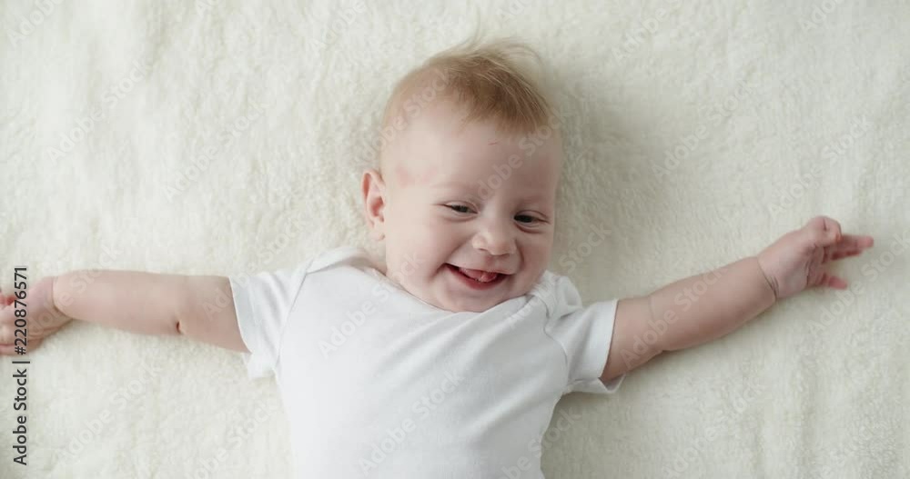 Little caucasian child happily smiling and laughing, lying on white bed sheet. happy childhood concept closeup 4k Little caucasian child happily smiling and laughing, lying on white bed sheet. happy childhood concept closeup 4k