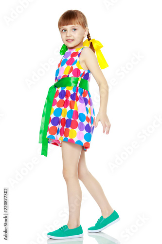 A little girl in a dress with a pattern from multi-colored circl