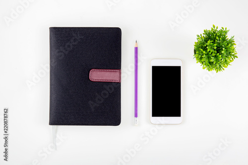 Black cover leather notebook or diary for reminder and memo isolated on white background, book mockup pencil tree and smart phone on desk office, education and supplies concept, top view. photo