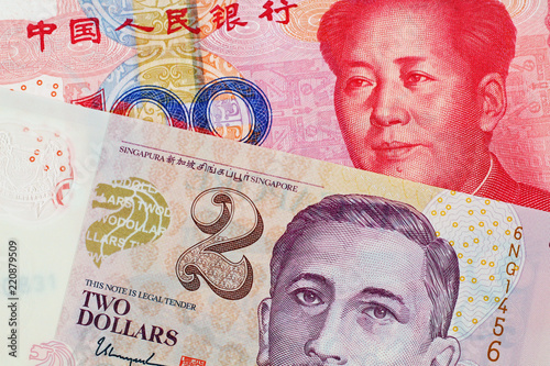 A close up image of a two Singapore Dollar bank note with a hundred Chinese Yuan bank note