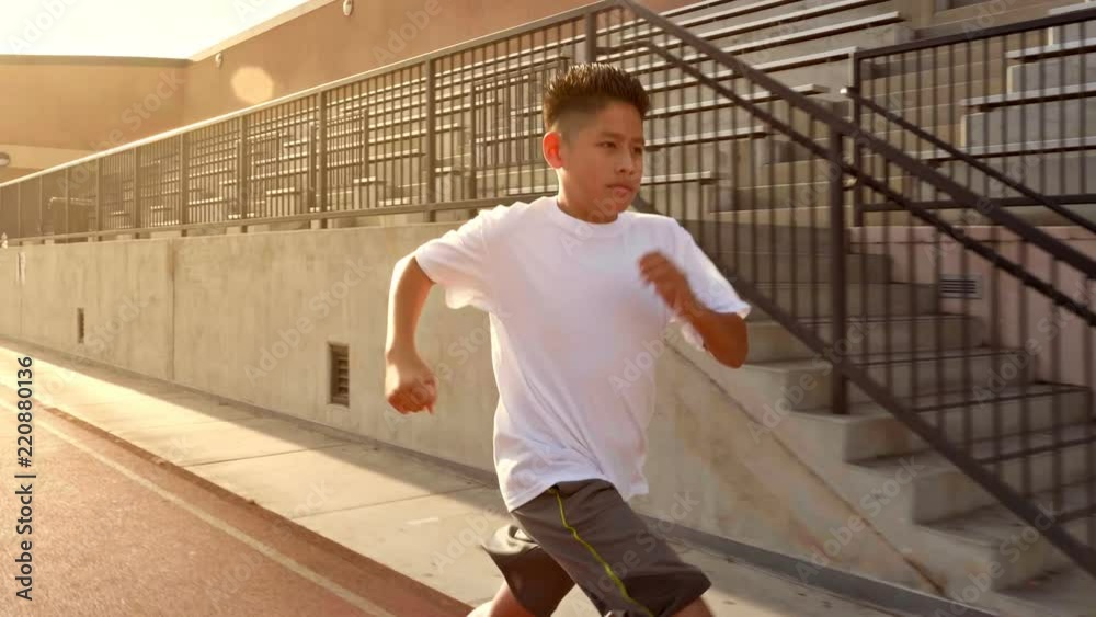 12 year old boy runs on his school's track.