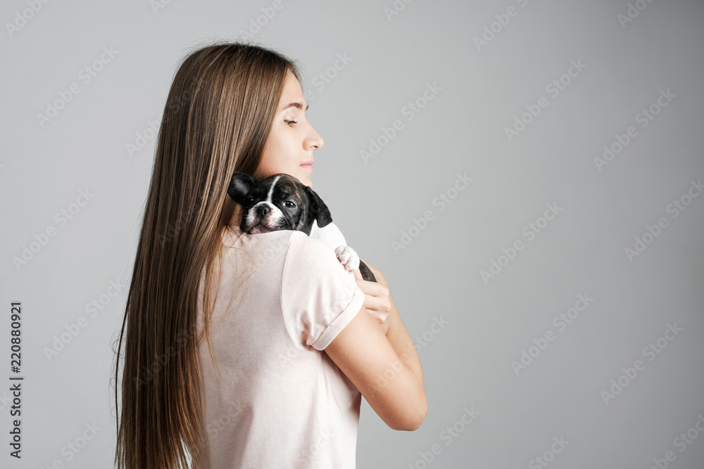 Young beautiful girl hugging a puppy of a French bulldog