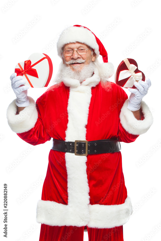 Christmas. Smiling Santa Claus in white gloves holds two red and white heart shaped gift boxes with a ribbon. The concept of generous gifts. Isolated on white background. Christmas. Smiling Santa Claus in white gloves holds two red and white heart shaped gift boxes with a ribbon. The concept of generous gifts. Isolated on white background.