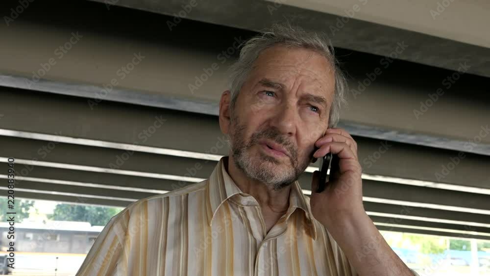 An Elderly Man Standing Under The Overpass And Talking On A Mobile Phone An Elderly Man Standing Under The Overpass And Talking On A Mobile Phone