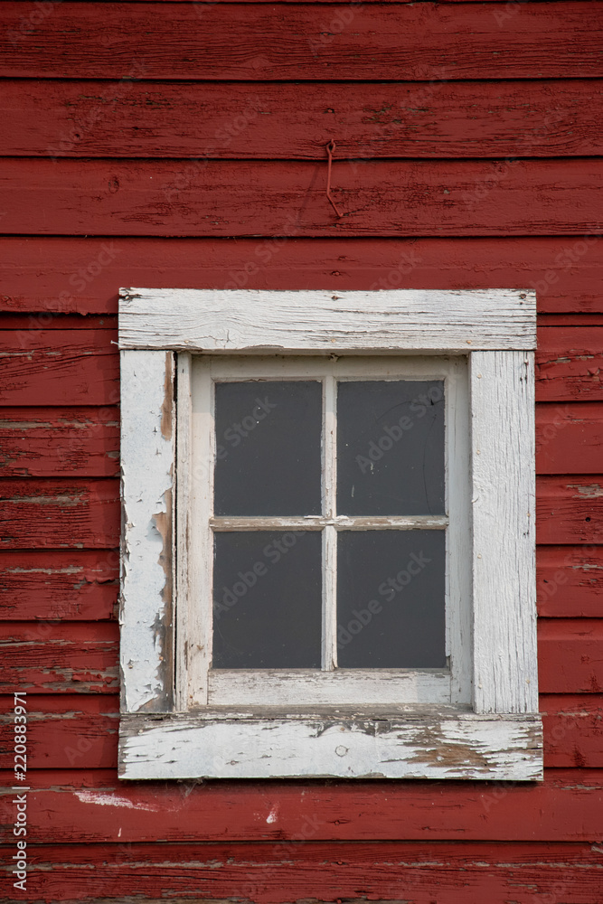 Square window with a white frame on an old red barn