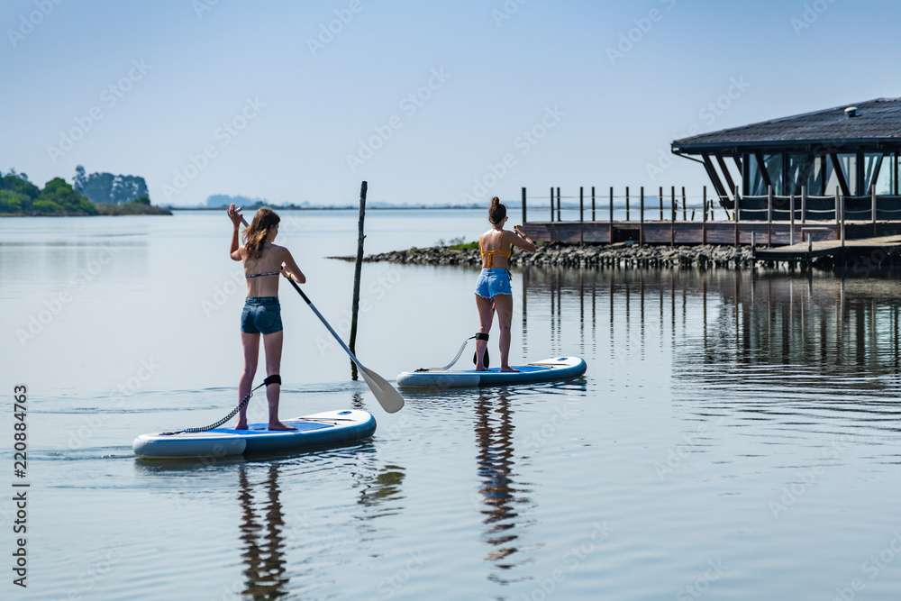 Two women stand up paddleboarding