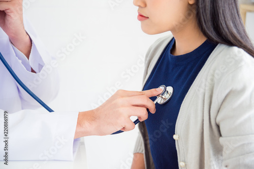 Doctor checking patient's heartbeat by stethoscope at hospital