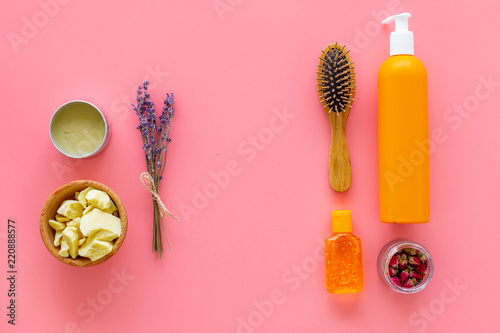 Cosmetics for hair care with jojoba, argan or coconut oil. Bottles and pieces of oil on pink background top view pattern copy space