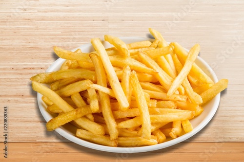 Plate of french fries on wooden table