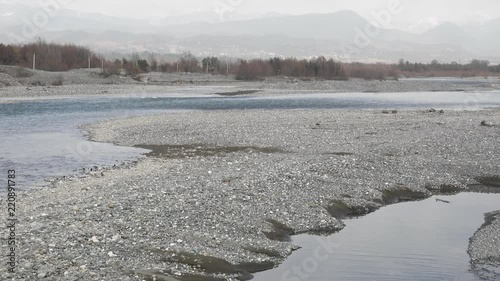 The mouth of the border river Chorokh. Georgian side. On the horizon are visible foothills, peaks of the Caucasus in the foreground powerful pebble sediments in the winter dries
 photo