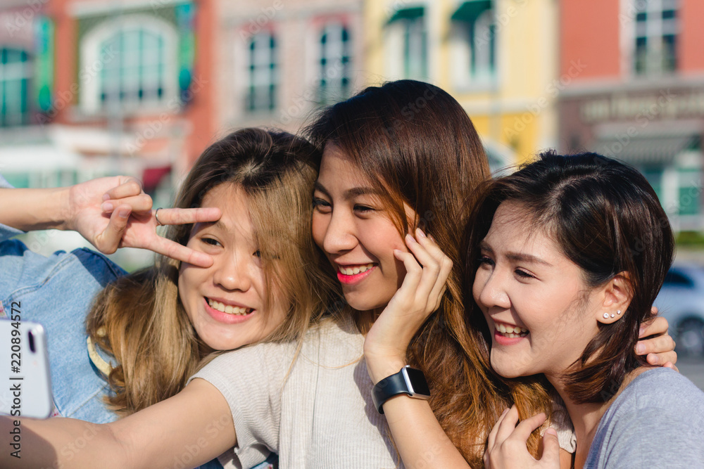 Obraz premium Attractive beautiful asian friends women using a smartphone. Happy young asian teenage at urban city while taking self portraits with her friends together with a smartphone.
