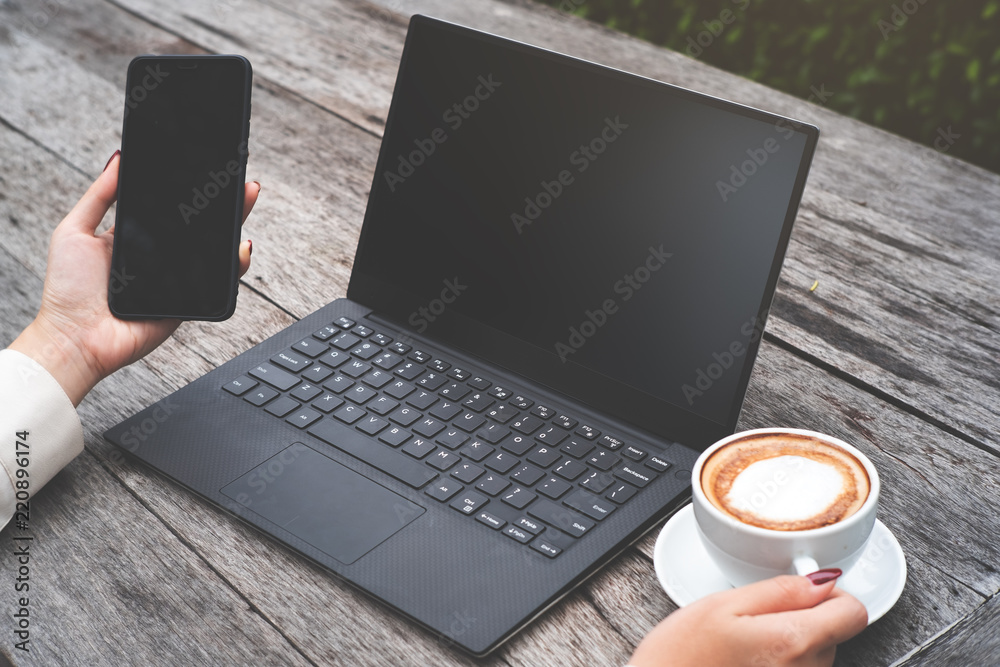 Mock up image of woman hold smart phone and laptop on wood table, and one hand hold coffee cup. Mock up image of woman hold smart phone and laptop on wood table, and one hand hold coffee cup.