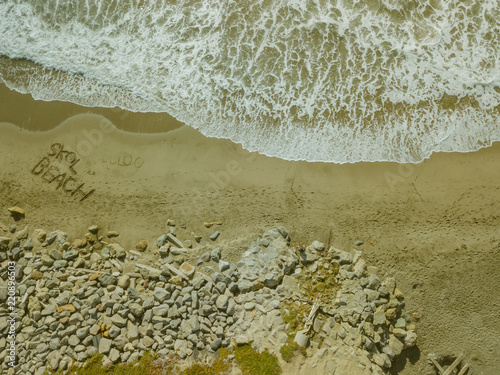 Aerial Top Down Drone View of Beach waves Writing in Sand