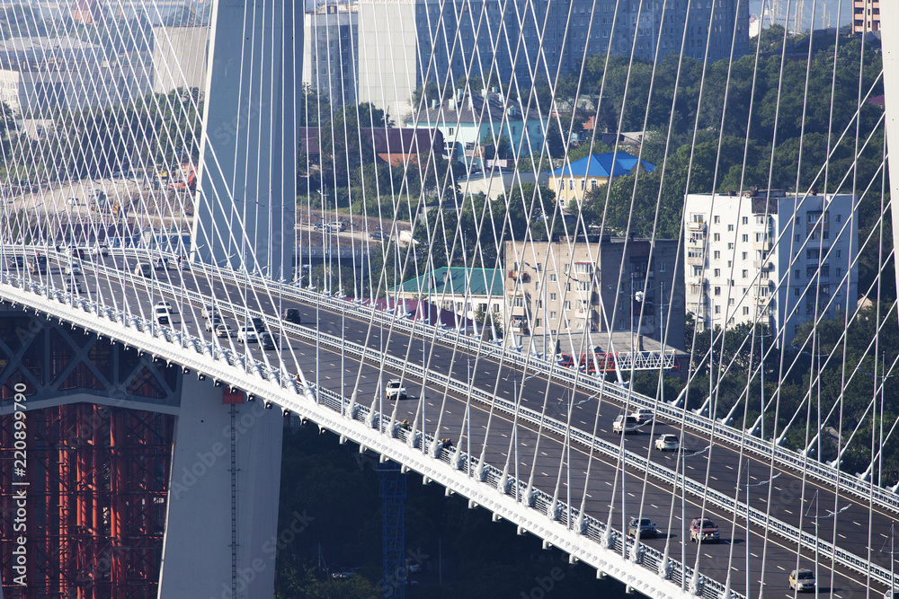 Fototapeta premium Golden cable-stayed bridge road car traffic from above. Modern Vladivostok Russia night illumination. Old and modern central buildings.