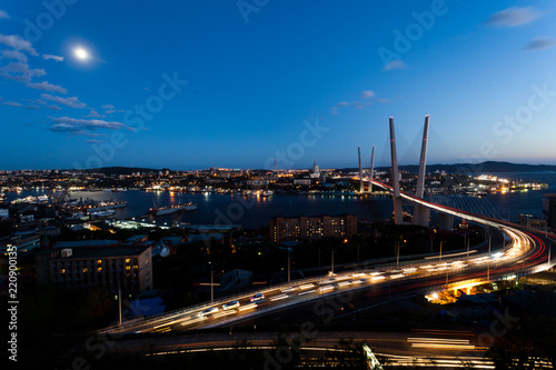 Golden cable-stayed bridge road car traffic from above. Modern Vladivostok Russia night illumination. Old and modern central buildings. © alexhitrov