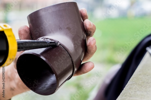 Canvas-taulu men's hands lubricate the gutter with a sealing agent