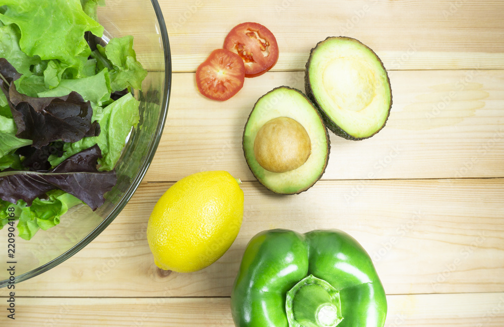 Healthy salad diet food concept, props decoration tomatoes, lemon, Green pepper, avocado, green and Purple Salad in Glass Plate on wood floor background, top view. Copy Space. Healthy salad diet food concept, props decoration tomatoes, lemon, Green pepper, avocado, green and Purple Salad in Glass Plate on wood floor background, top view. Copy Space.