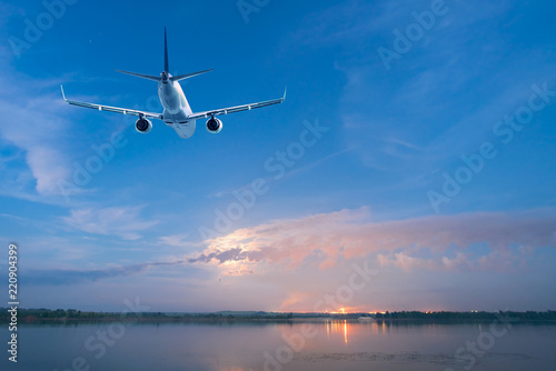 Airplane flying over the water at dusk