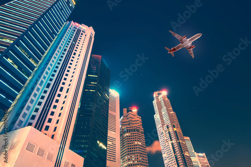 Airplane flying over skyscrapers at night