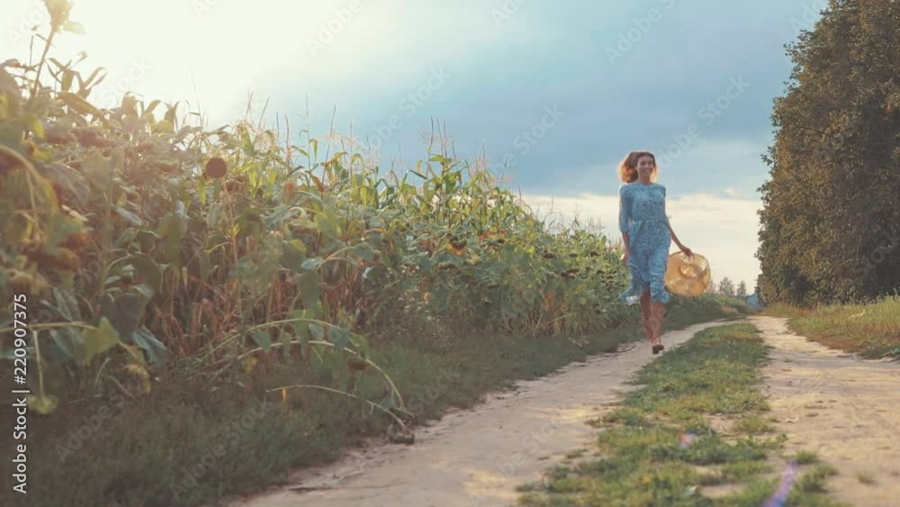 beautiful sweet girl in a blue dress and hat running toward camera on a field of sunflowers , woman enjoying summer day, countryside style, lifestyle slow motion video shooting by handheld gimbal beautiful sweet girl in a blue dress and hat running toward camera on a field of sunflowers , woman enjoying summer day, countryside style, lifestyle slow motion video shooting by handheld gimbal