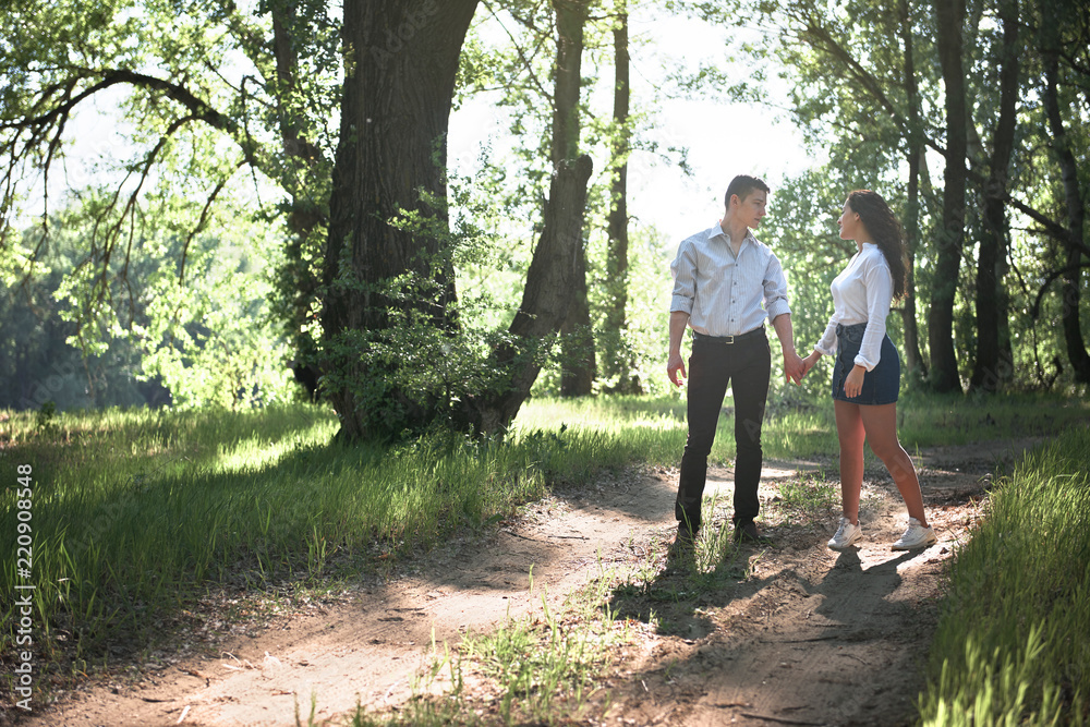 young couple walking in the forest, summer nature, bright sunlight, shadows and green leaves, romantic feelings young couple walking in the forest, summer nature, bright sunlight, shadows and green leaves, romantic feelings