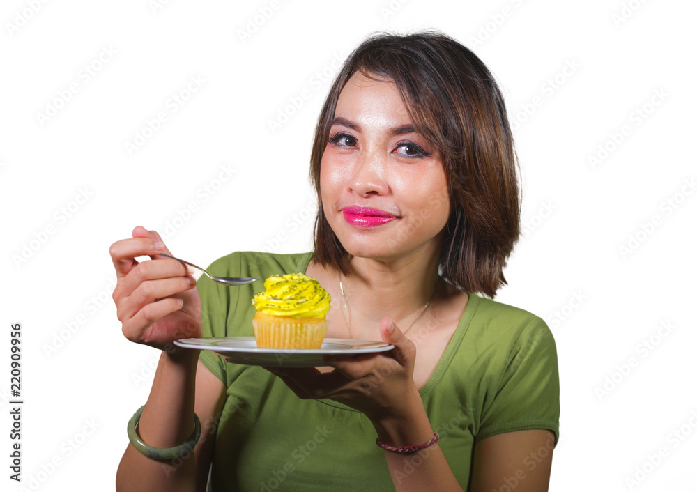 young beautiful and happy hispanic woman eating tasty and delicious yellow sugary cupcake posing on isolated background in sugar and sweet addiction young beautiful and happy hispanic woman eating tasty and delicious yellow sugary cupcake posing on isolated background in sugar and sweet addiction