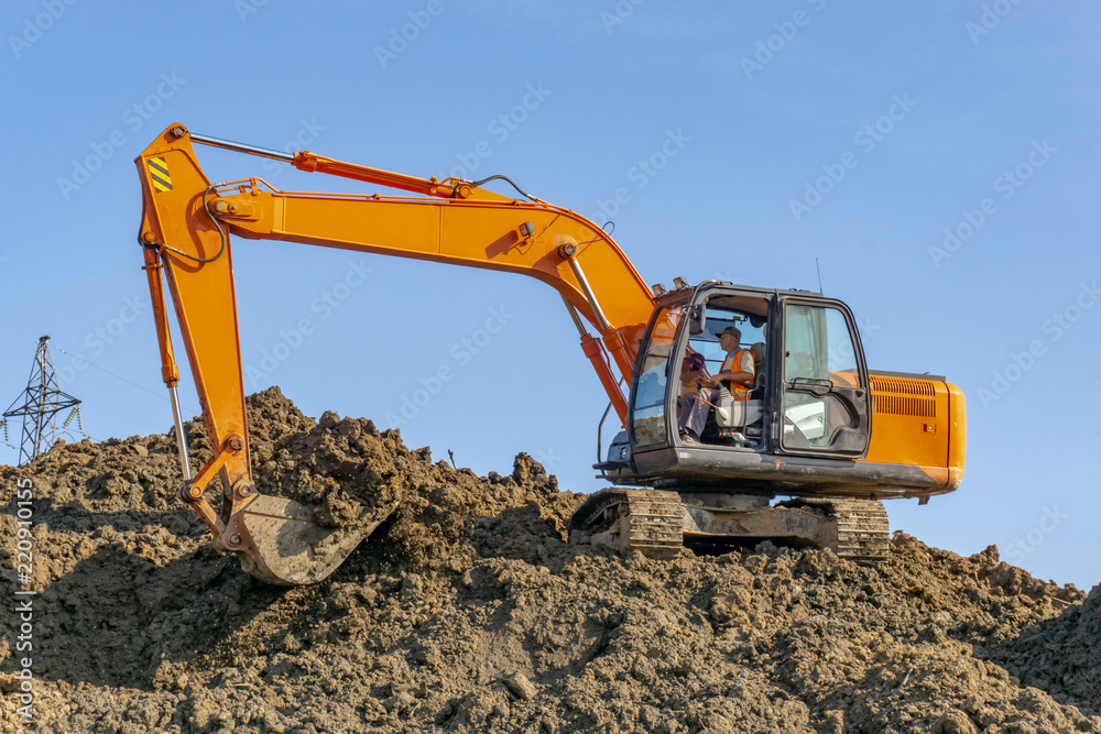 Orange excavator loads the land on a construction site.. Orange excavator loads the land on a construction site..