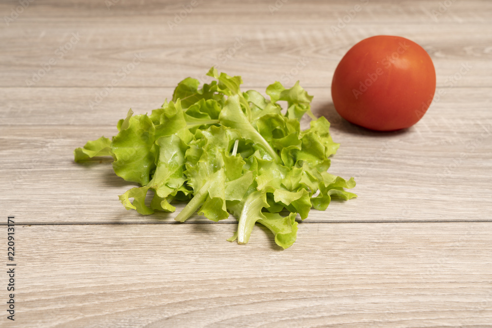 a tomato, cucumber and salad on a wooden table a tomato, cucumber and salad on a wooden table